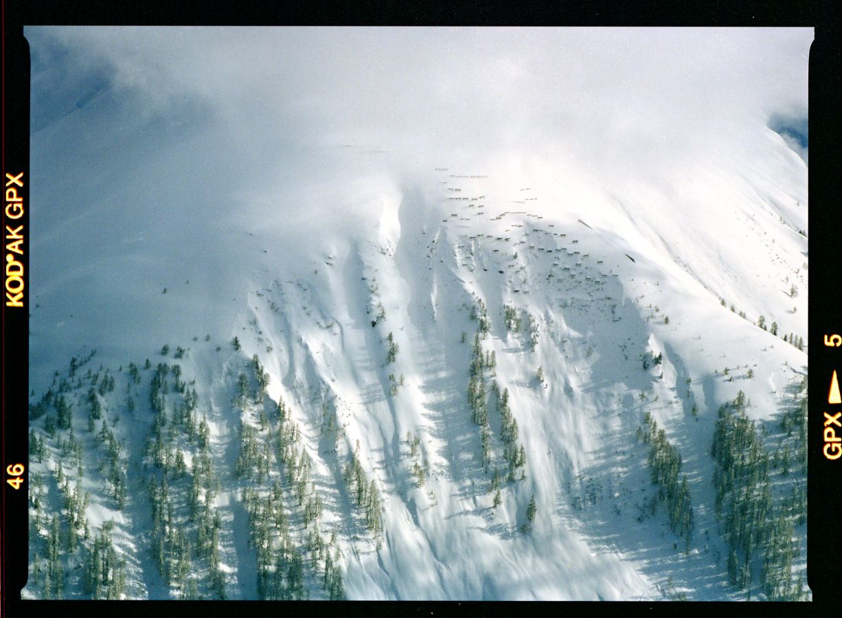 Nochmals das Gebiet Raifte. Im verbauten Gebiet variieren die Schneehöhen stark: Während auf einigen Werken wenig Schnee liegt, sind andere völlig eingeschneit und kaum noch erkennbar. Auch die Triebschneewand links wurde zu einem grossen Teil überschneit. Aufnahmerichtung: NW, 25. 02. 1999, 15:30; Titel der Aufnahme: SCHLIECHT, MÜNSTER; Goms, Wallis Kameramodell: Expression 12000XL